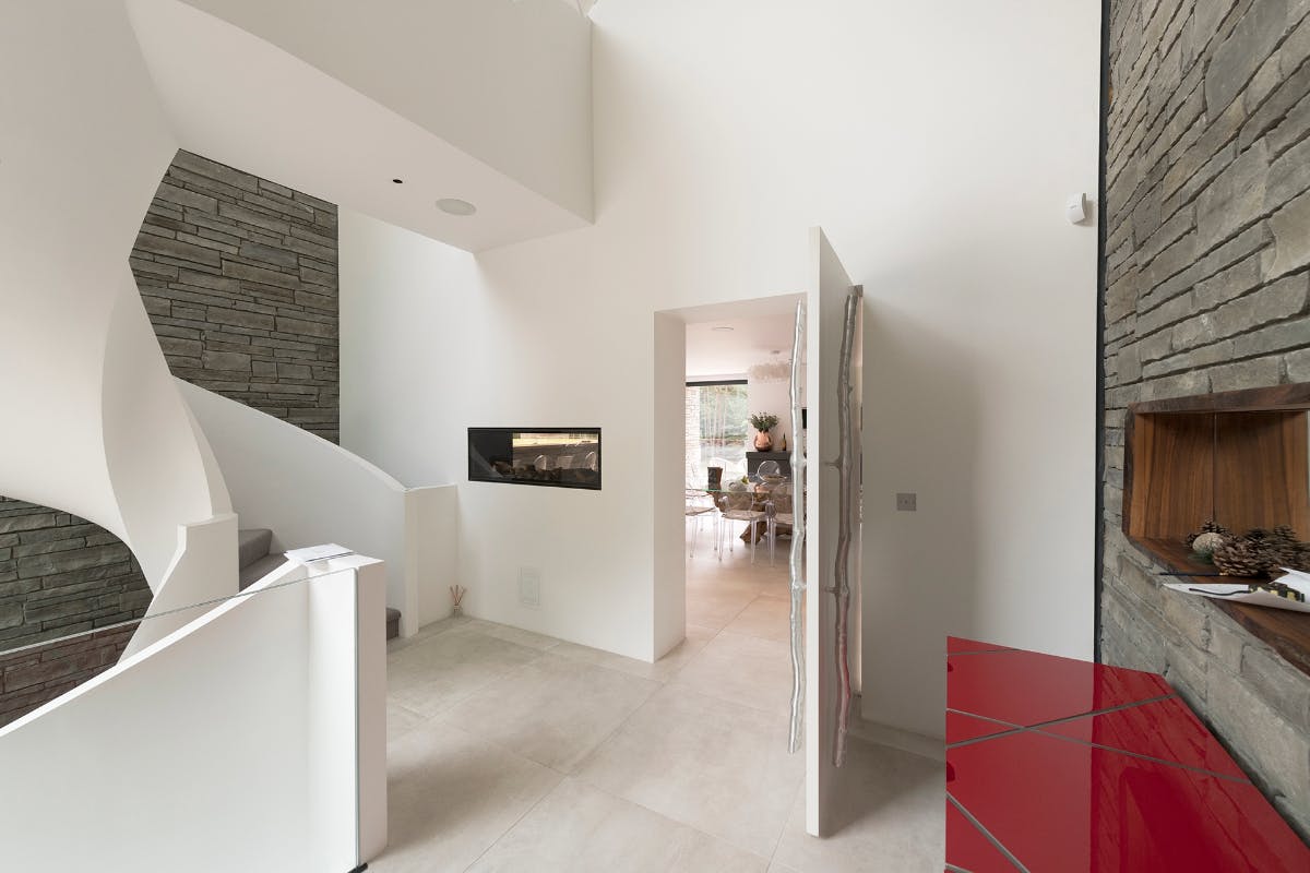 Open bespoke pivot door in Trem, painted white in a contemporary hallway