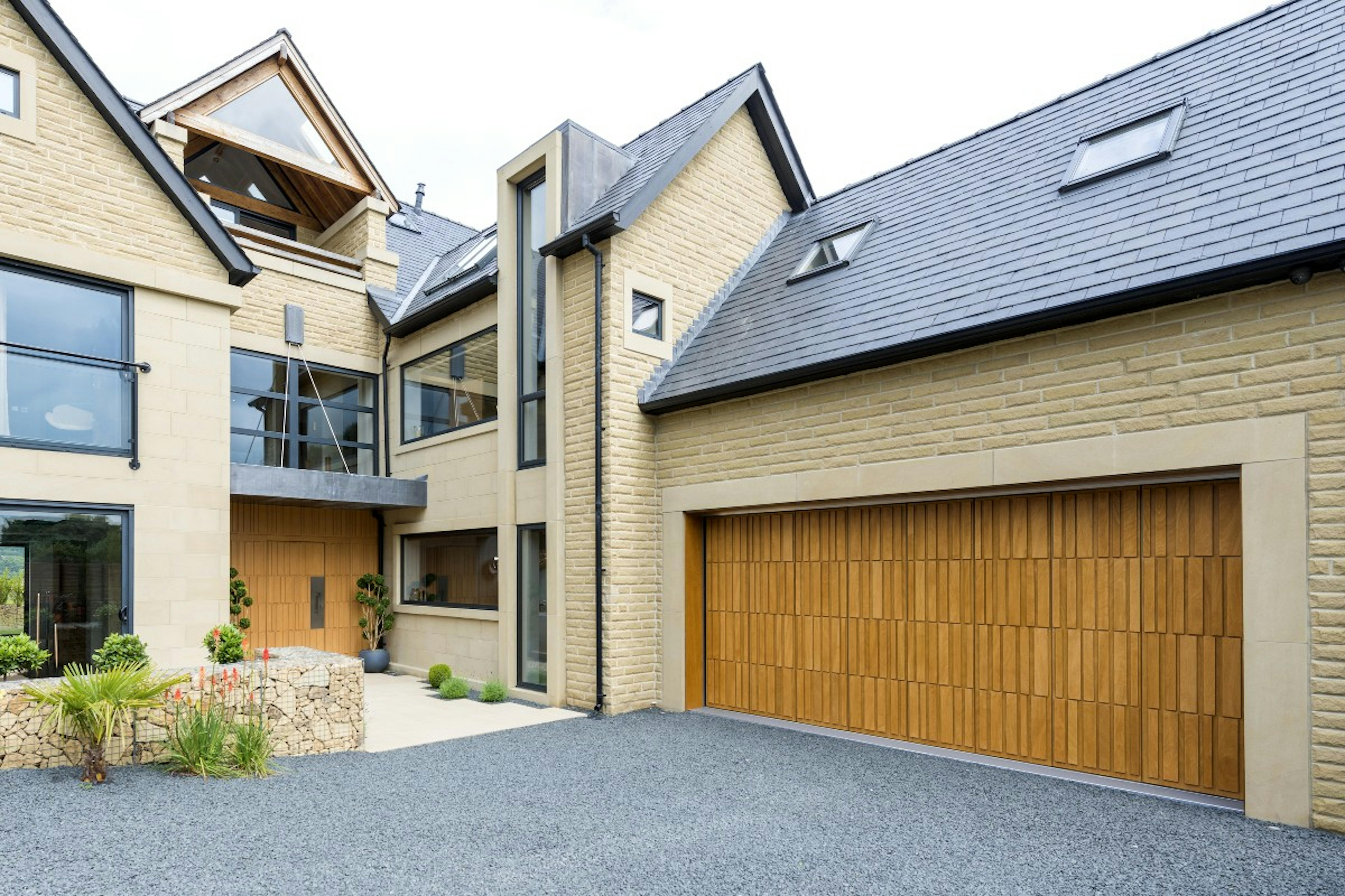 Self-build home exterior with matching contemporary front and garage doors by Deuren - style is Tavole in honey oak finish. 