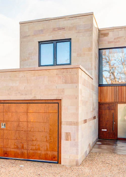 exterior of modern stone house with bespoke Olivo SI front and garage doors