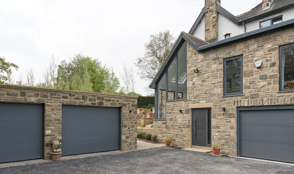 A modern residential building with a brick exterior and 3 garage doors