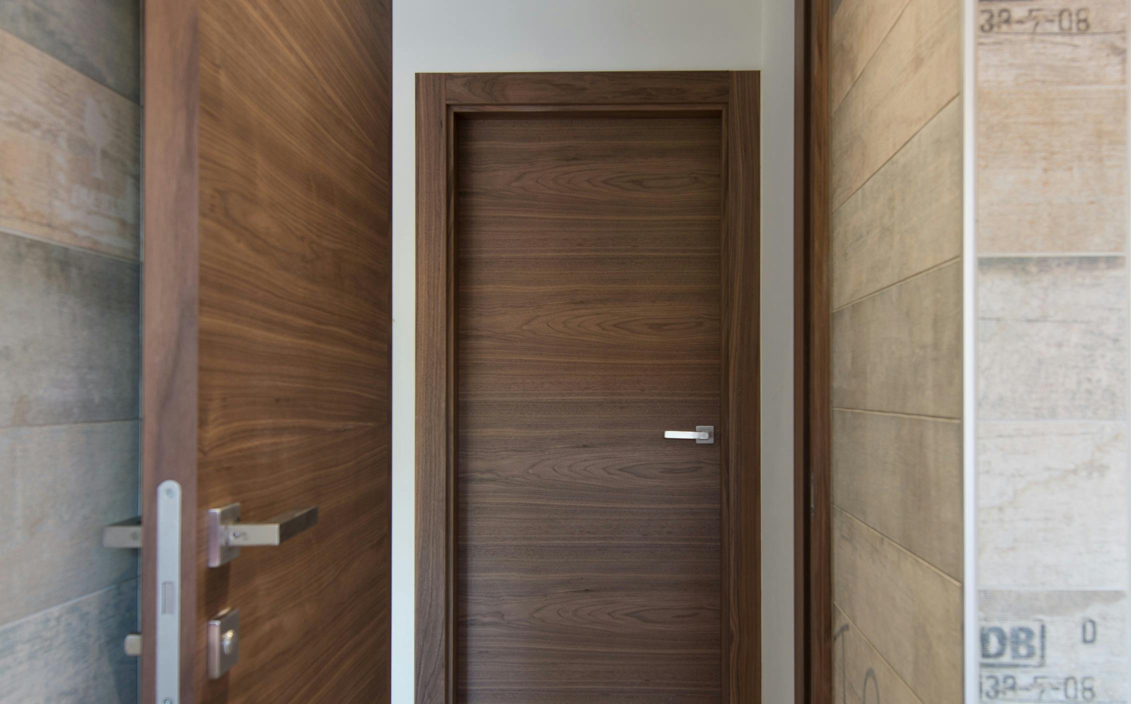 View of a contemporary door set,  through an open door. Deuren's Trem H style in Walnut finish with chrome lever handle.