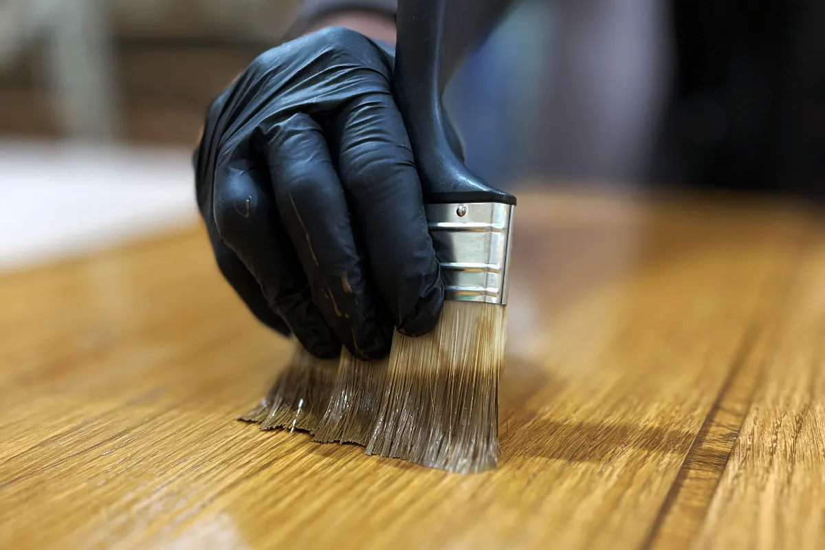 Deuren craftsman applying lacquer to a door panel with decorators brush
