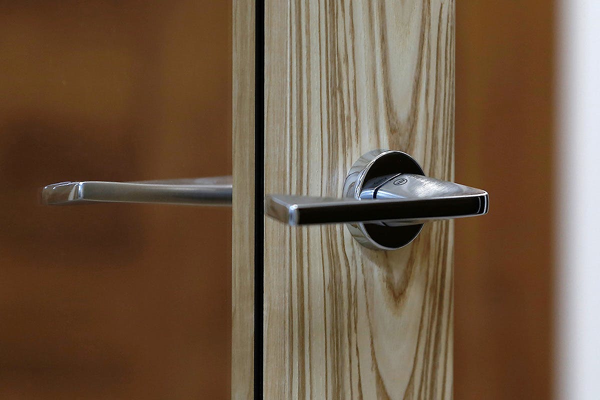 Close-up chrome lever handle on Olive oak door.