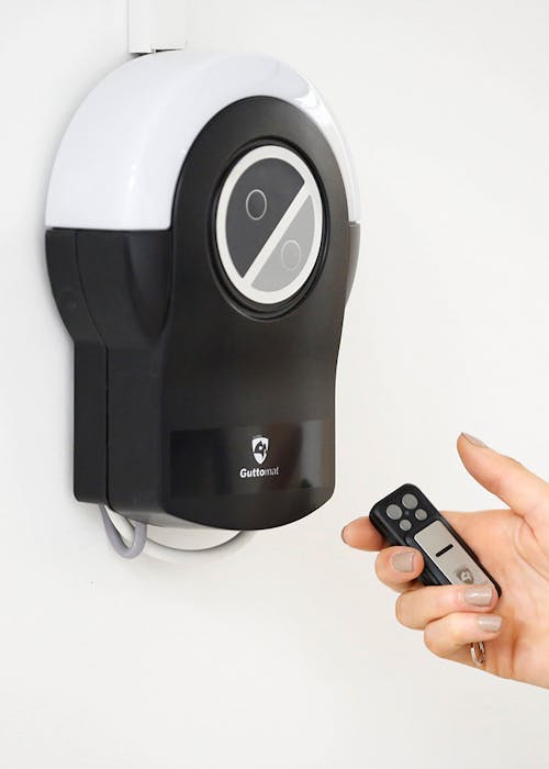 Close-up of a person's hand holding a remote control pointing towards a control unit.