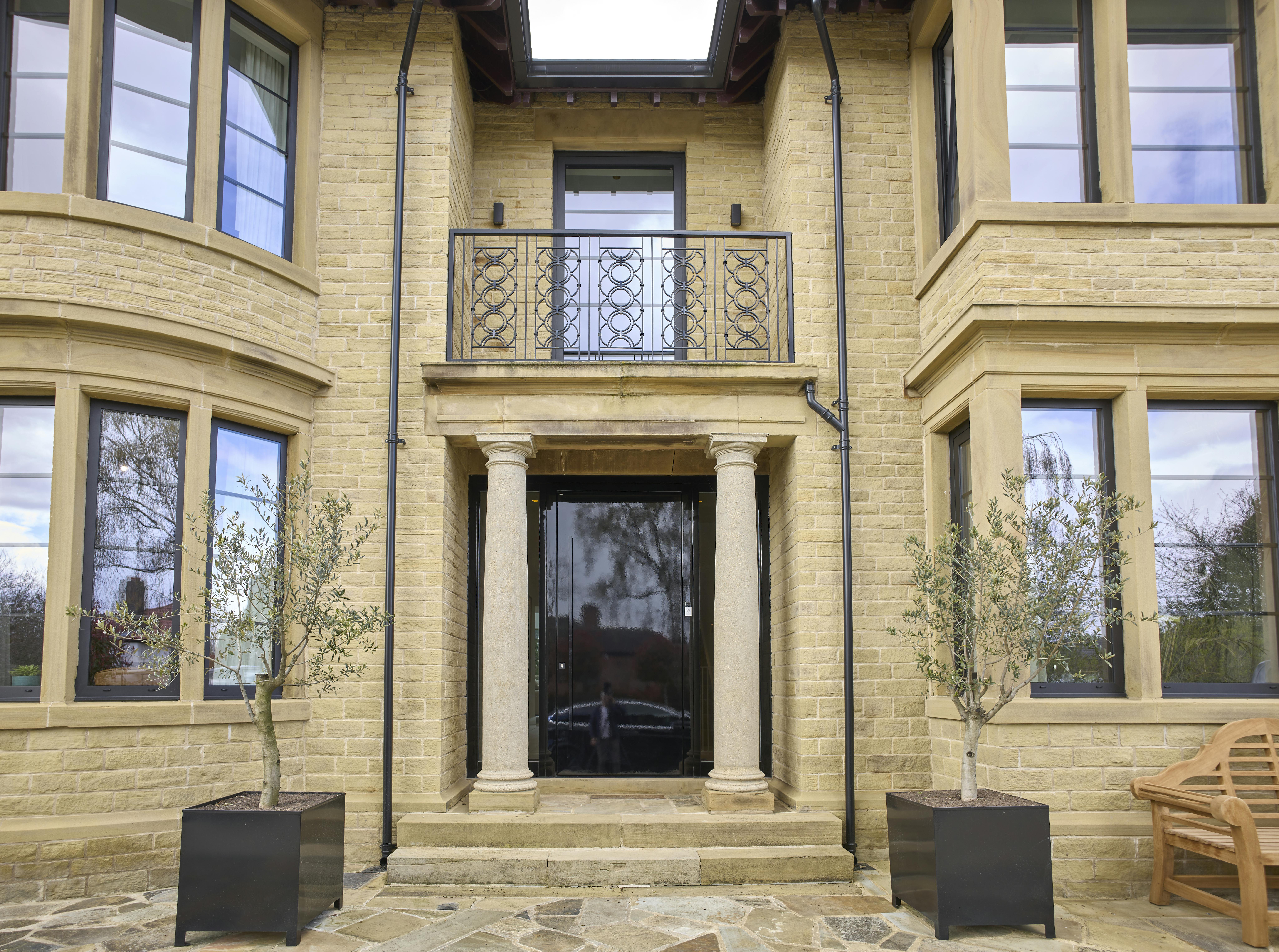 Glossy black entrance door surrounded with two stone pillars