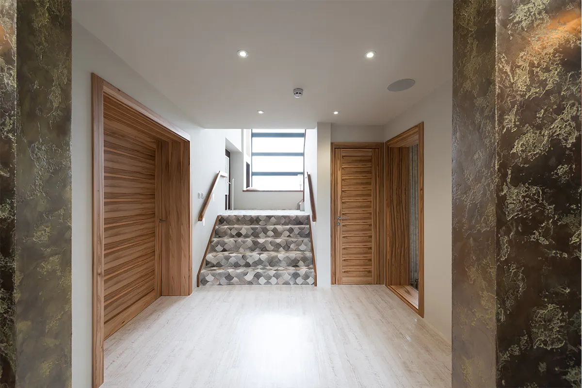 Self-build home hallway and staircase featuring two modern pre-hung door sets by Deuren in Gio Satin Walnut