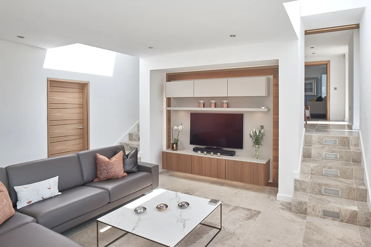 Drop level tv room with a single door set in satin walnut finish - Trem H door style by Deuren. Feature T.V. wall in matching satin walnut panelling.