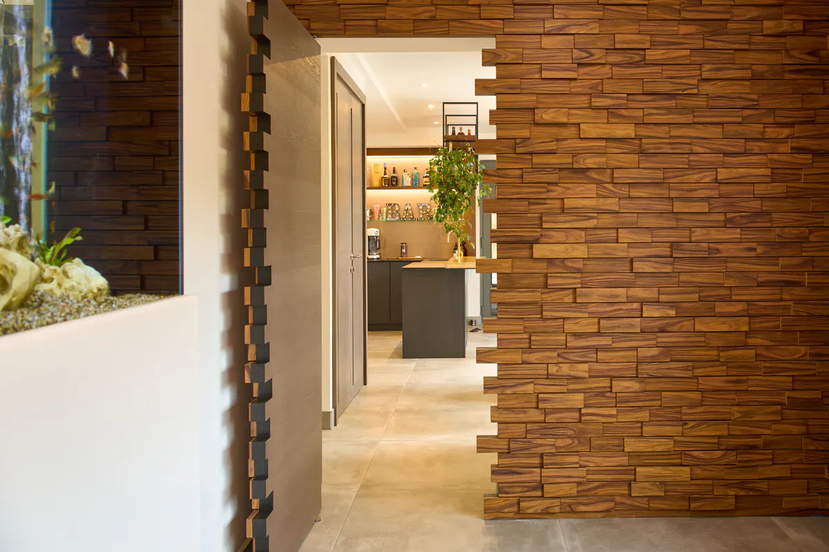 A bespoke secret pivot door by Deuren. Door and surrounding wall surfaces are finished in stacked tiber blocks. Door is disguised into the wall.
