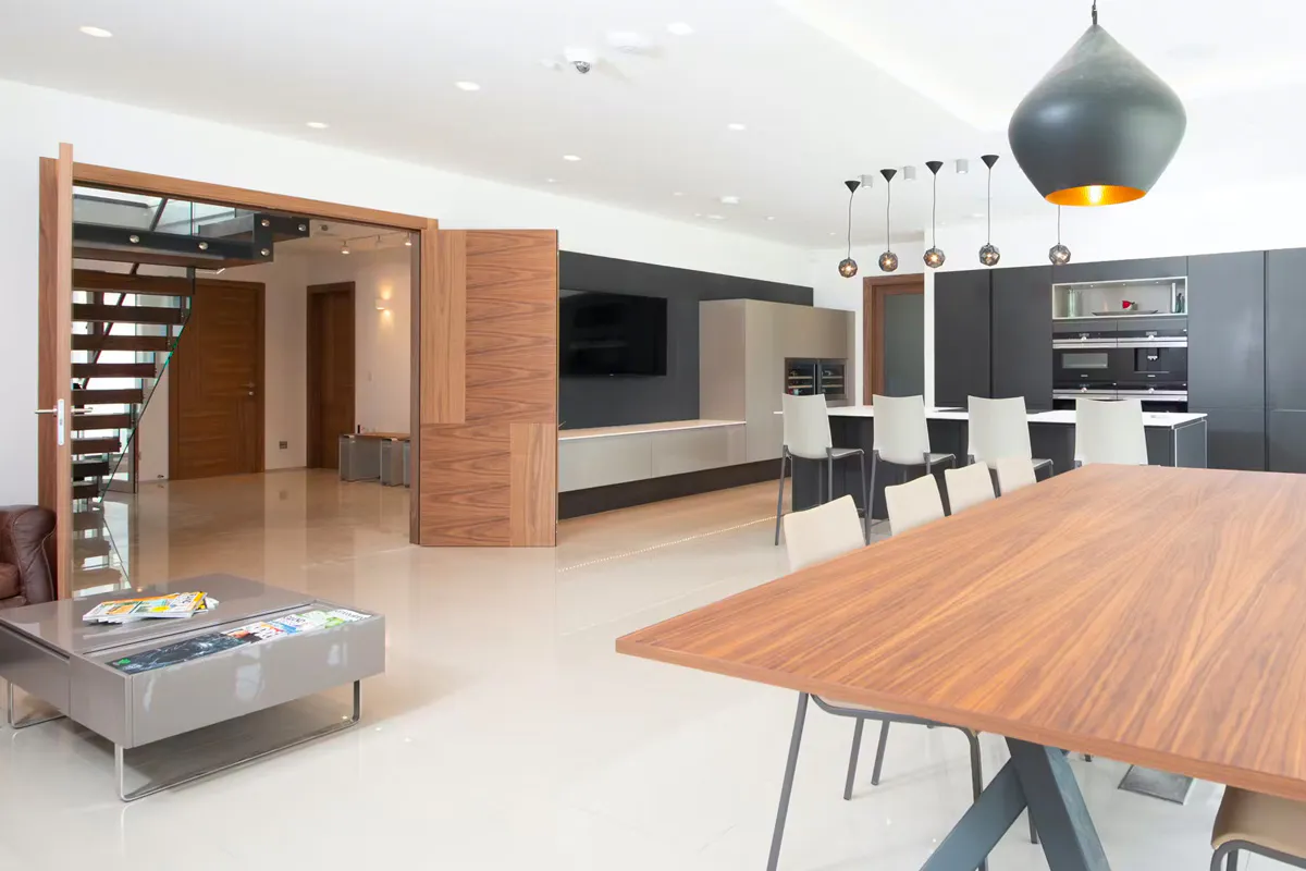 Large and modern open plan kitchen, dining and living area featuring a Deuren double leaf door set - Vario 4 style, in a walnut veneer finish.