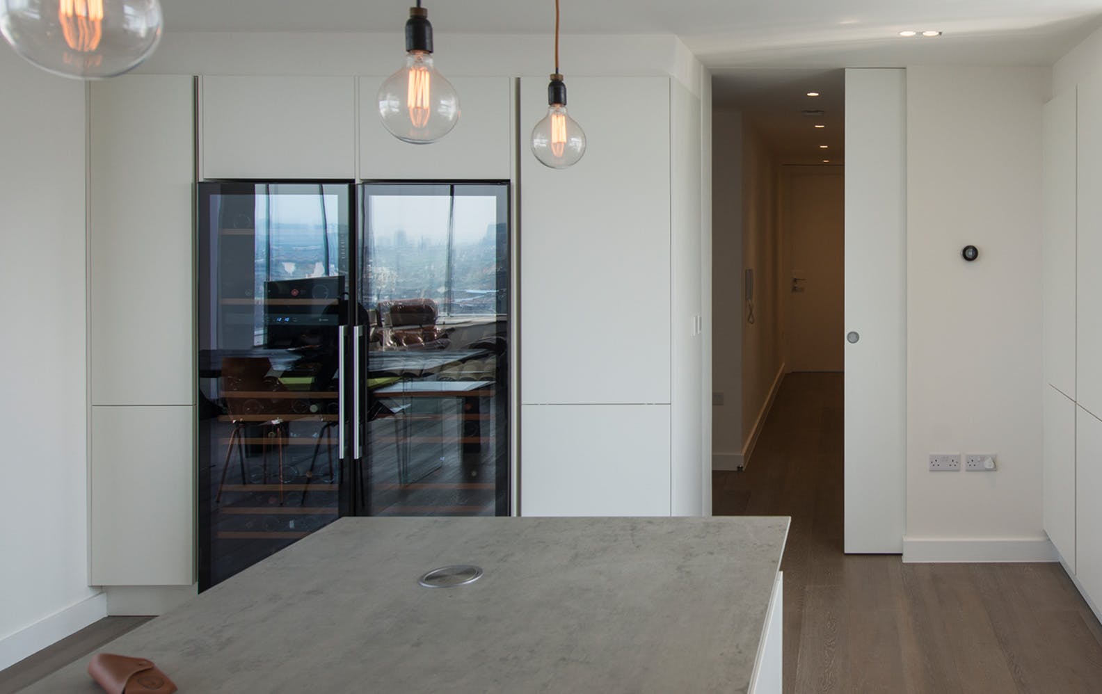 White, contemporary kitchen with a Deuren, full height pocket door - Trem, painted white. that opens on to a corridor.