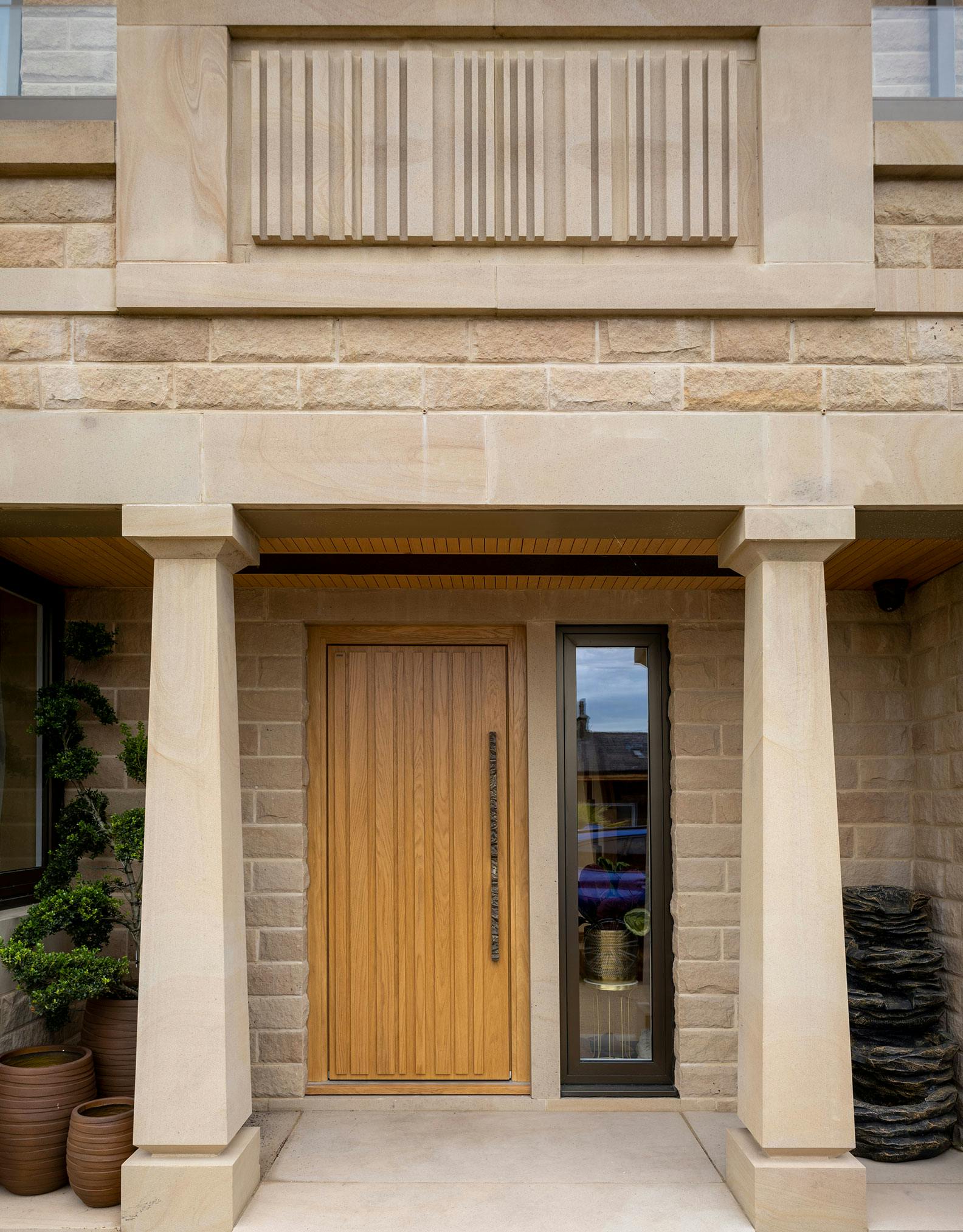 Light Yorkshire stone home entrance with a contemporary Deuren front door - The Pianura design has irregular vertical rised strips and is in a honey oak finish.
