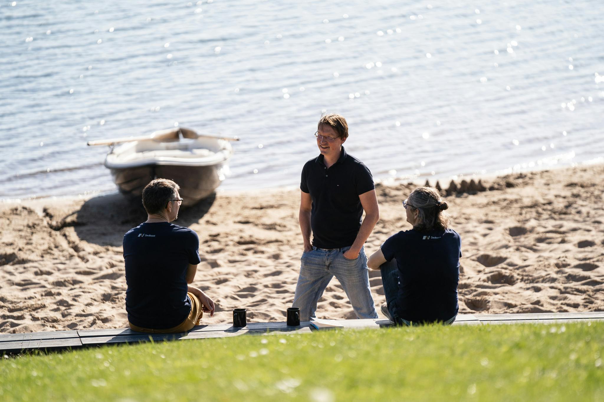Die drei DevBoost Geschäftsführer sitzen am See - es wird etwas diskutiert 