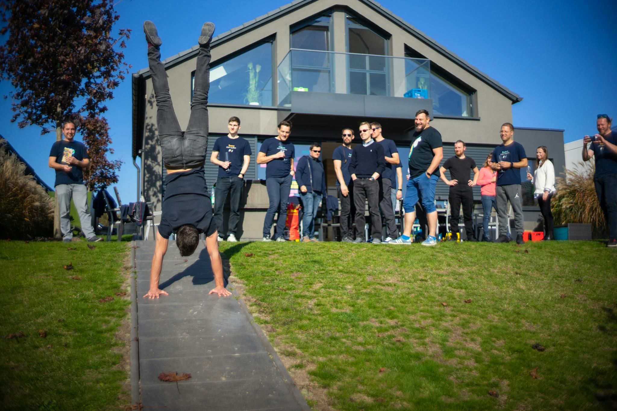 Person macht Handstand, andere Personen schauen begeistert zu