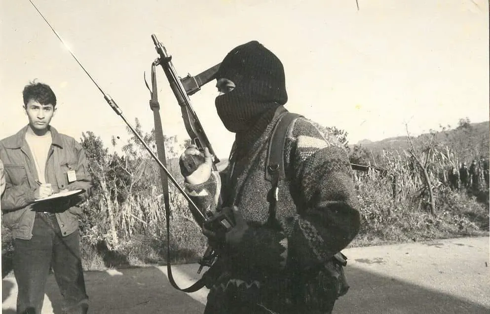 periodista toma nota junto a un insurgente armado