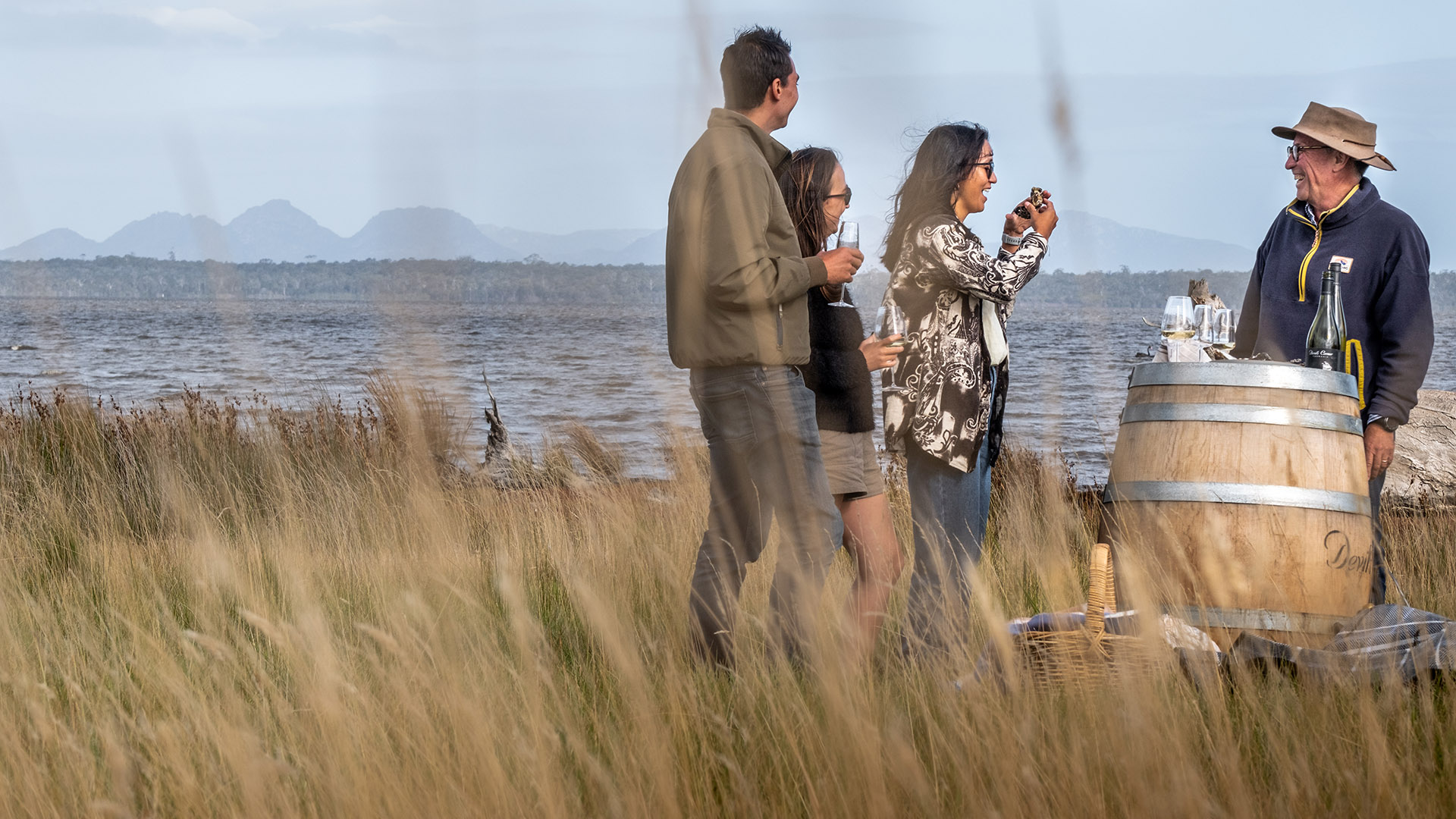 People gathered around a wine barrel drinking wine
