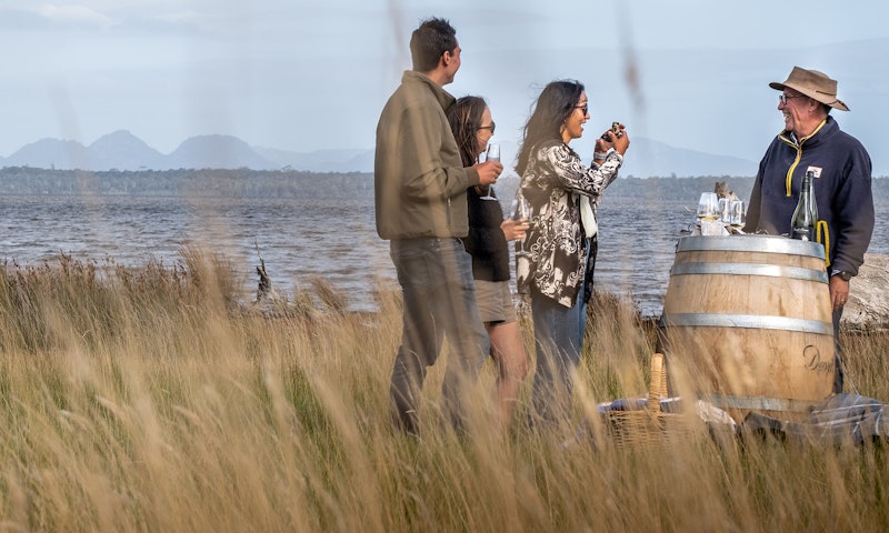 People gathered around a wine barrel drinking wine