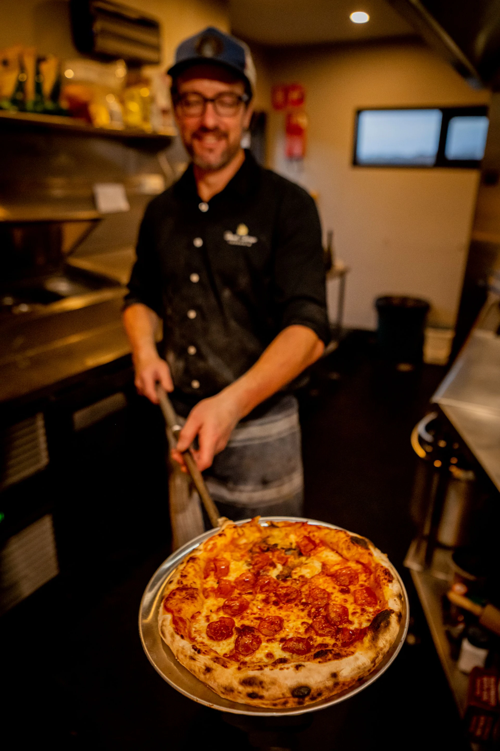 Pizza chef holding a pizza out of the oven