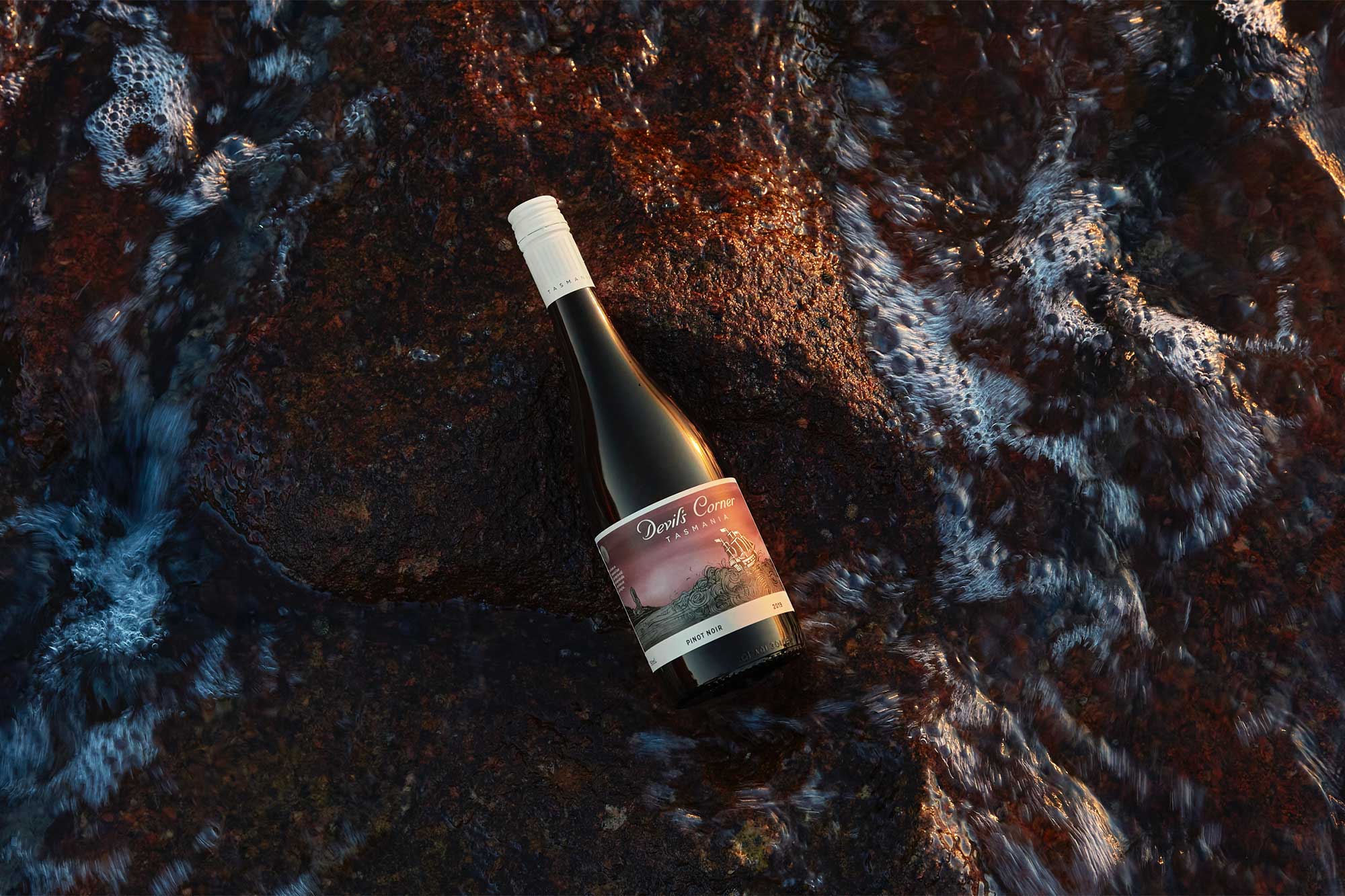 Devil's Corner Pinot Noir laying flat among the rocks and water