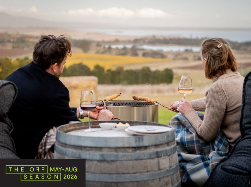 A man and woman sitting by the fire while enjoying a glass of wine