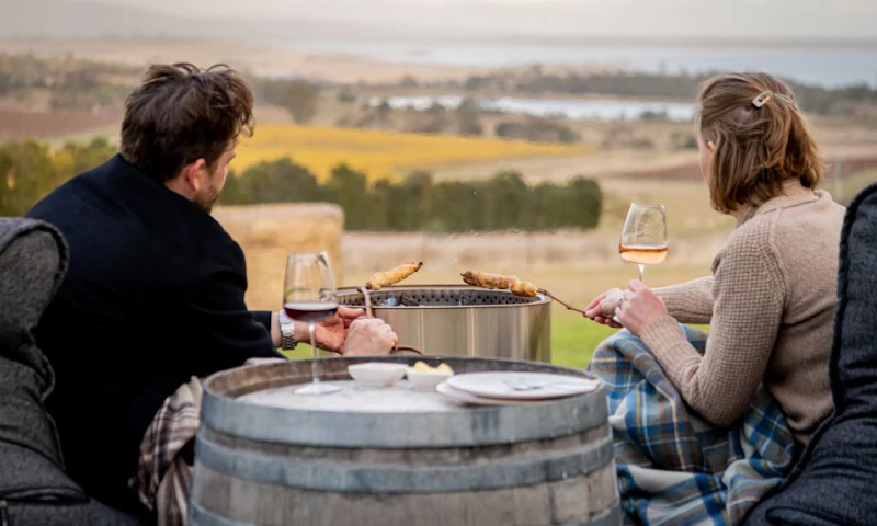 A man and woman enjoying a glass of wine by the fire