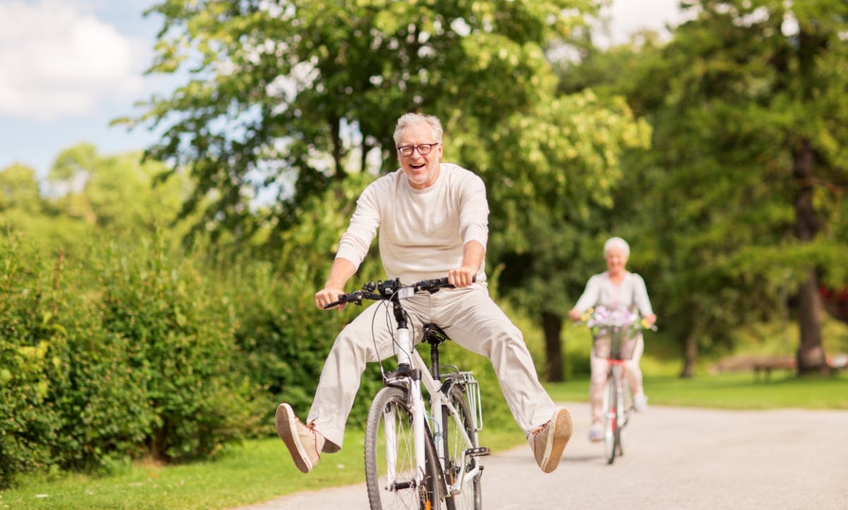 Happy senior couple riding bicycles in the park.