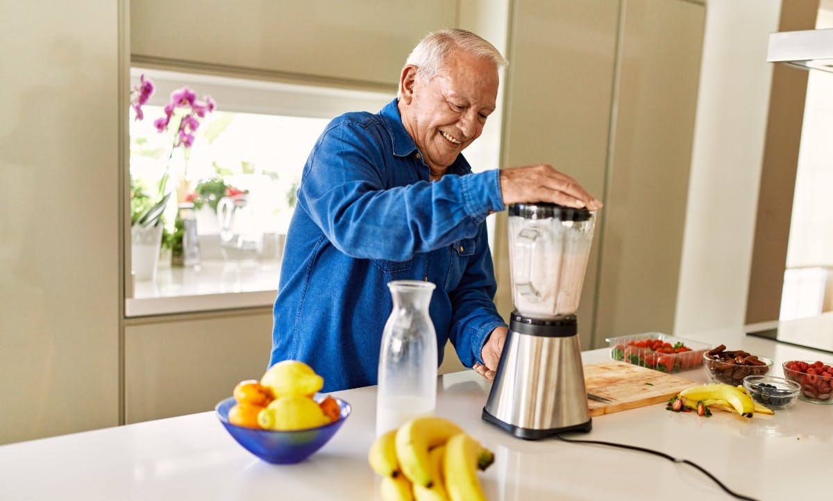 a man in his kitchen using a blender