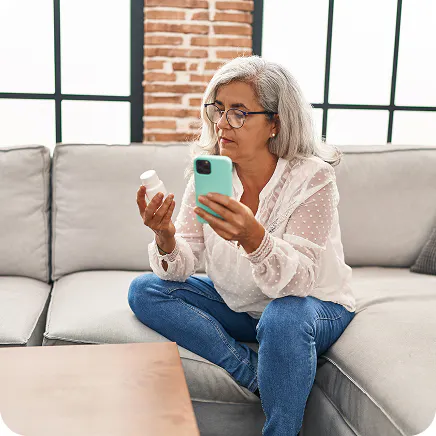 Medicare beneficiary reviewing prescription drug coverage and medication details on a phone.