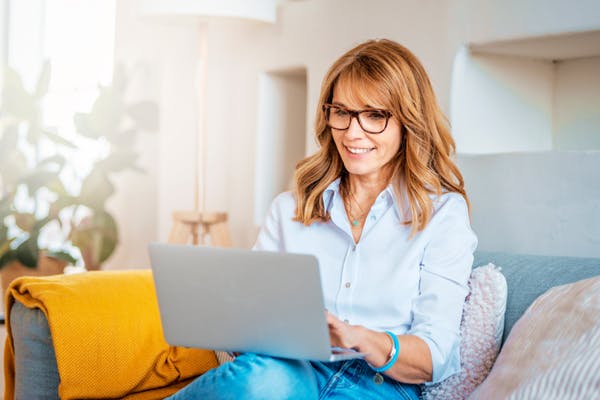 Woman sitting on the couch using a laptop.