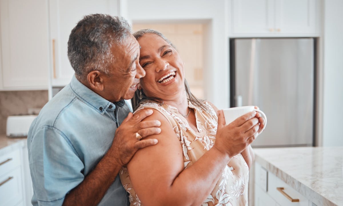 Man and a woman talking and smiling in the kitchen.