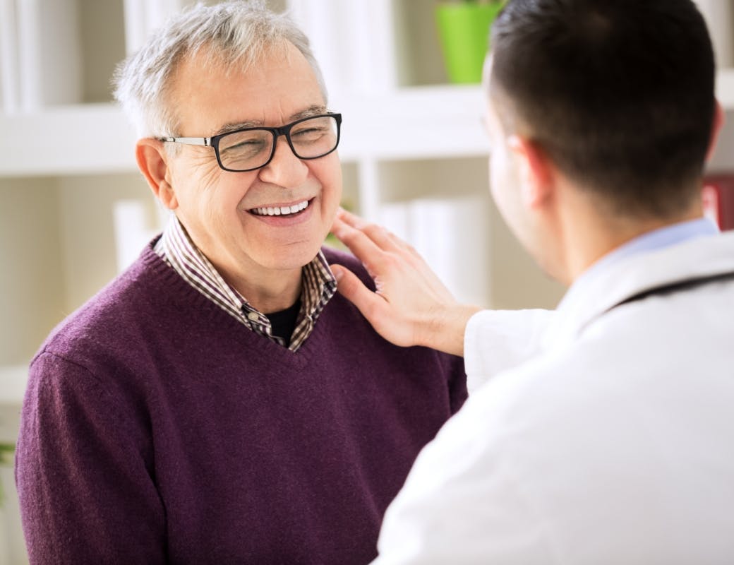 Smiling happy old male patient visiting with his doctor.