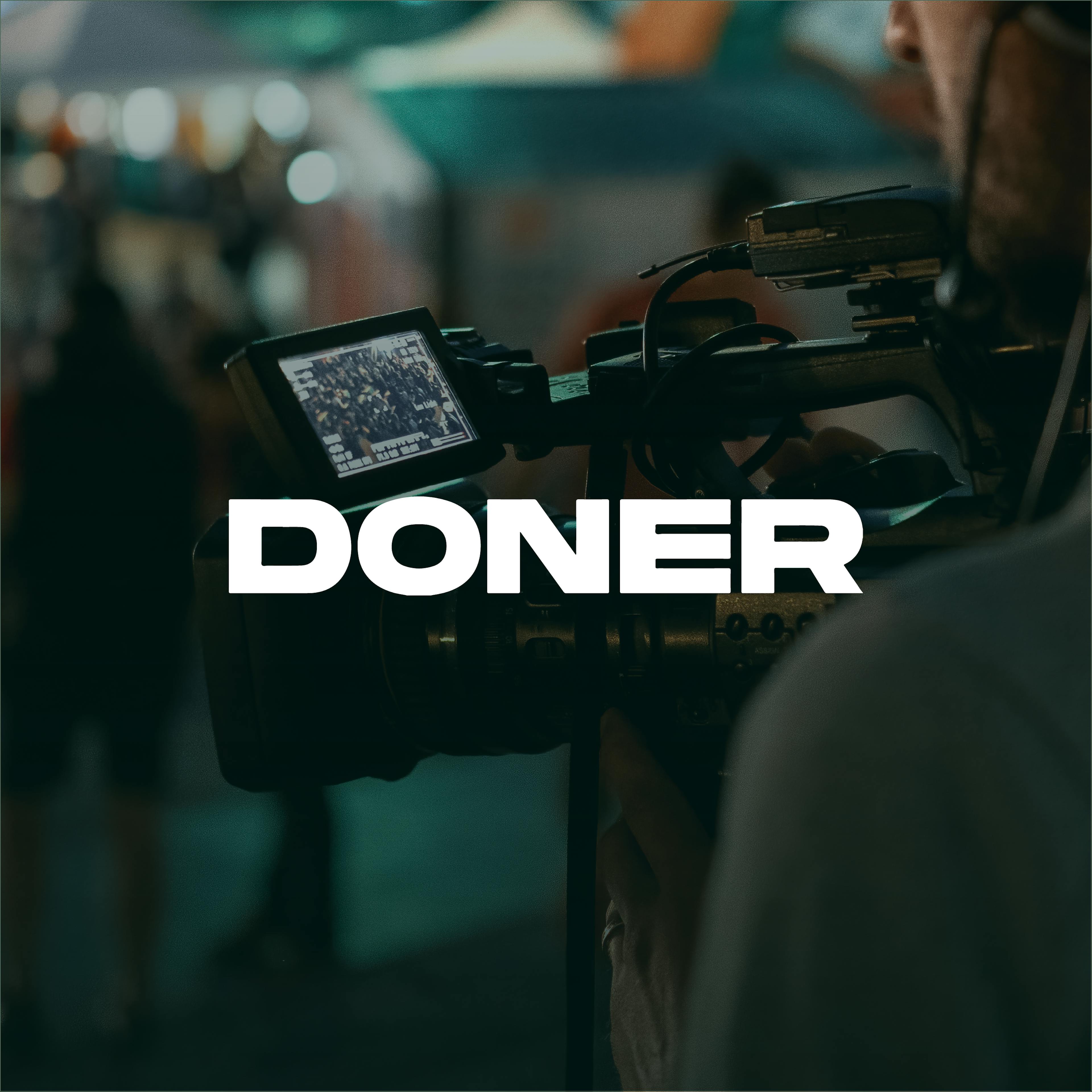 Camera operator filming with 'DONER' text overlay.