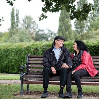 Two people smiling at each other on a bench.