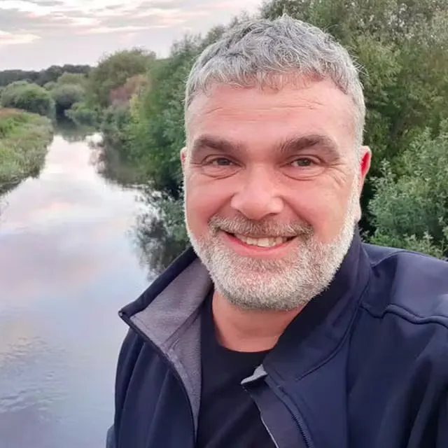 Image of Steve smiling in front of a scenic background at dusk