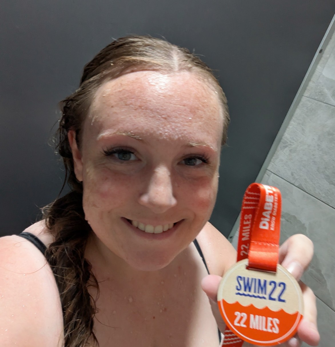Women holding swim22 medal, 22 miles