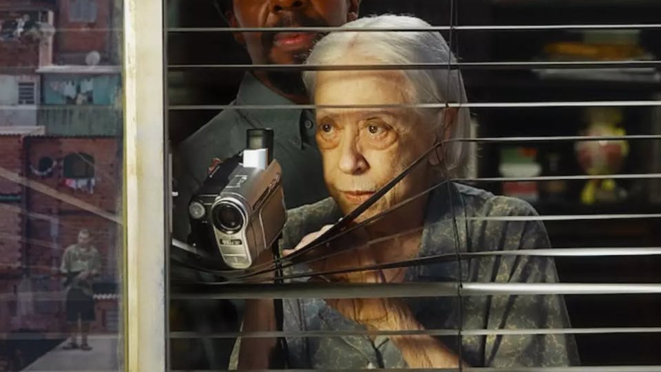 imagem de Fernanda Montenegro olhando pela janela com uma câmera na mão no filme Vitória