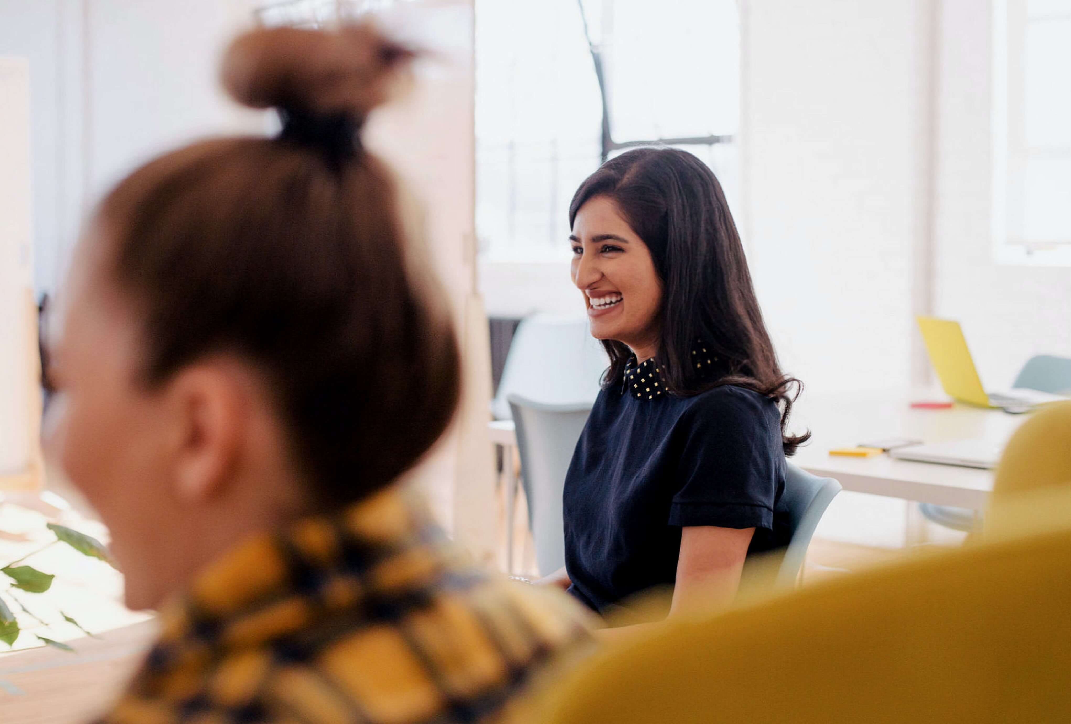 two women sitting in an office smiling
