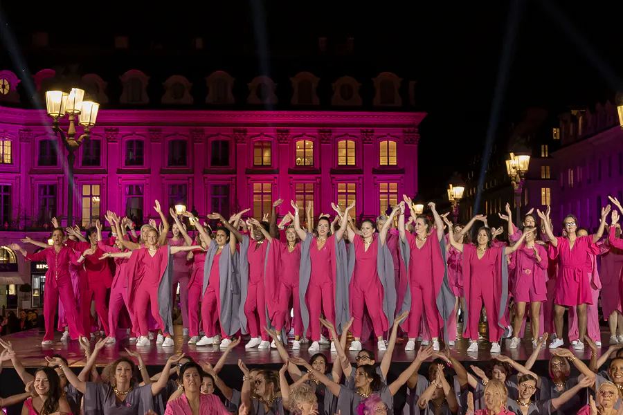 Des participantes en tenue rose réunies sur scène place Vendôme lors du lancement de la campagne Octobre Rose, porté par l'association Ruban Rose.