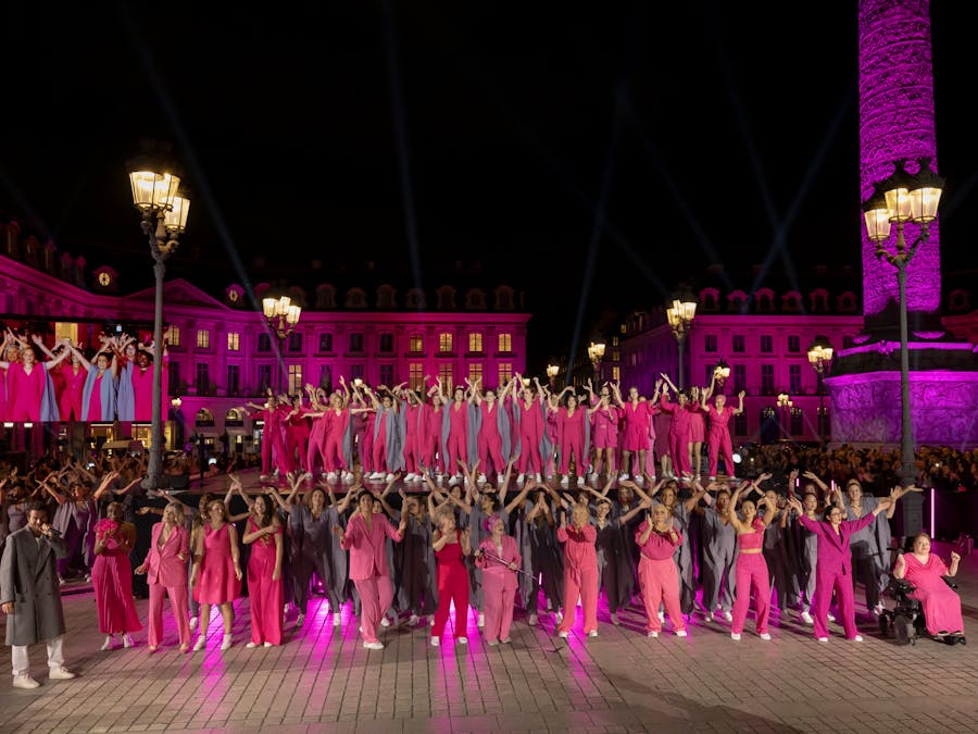 Une scène captivante lors d'Octobre Rose 2024, où une place publique est illuminée en rose pour soutenir la lutte contre le cancer du sein. Des participants vêtus de rose et de gris réalisent une danse synchronisée sous les lumières, symbolisant l'unité et l'engagement pour cette cause essentielle.