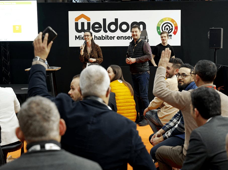 Intervenants animant une session interactive avec le public sur le stand Weldom lors d’un salon professionnel.