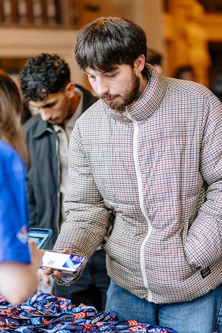 Participant récupérant un badge d’accès auprès du stand d’accueil lors d’un événement Domino’s Pizza.