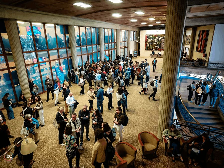 Participants discutant et réseautant dans le hall d’un lieu de conférence lors du Sommet de la mesure d’impact.