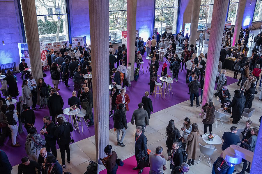 Attendees networking in the exhibition and networking area of the FEB Economic Forum at the Palais d’Iéna in Paris, with multiple stands and business meetings between participants.