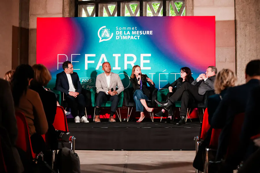 Panel discussion at the Sommet de la Mesure d'Impact, featuring speakers on stage engaging the audience around social impact topics, with a professional conference setup and live attendee participation.