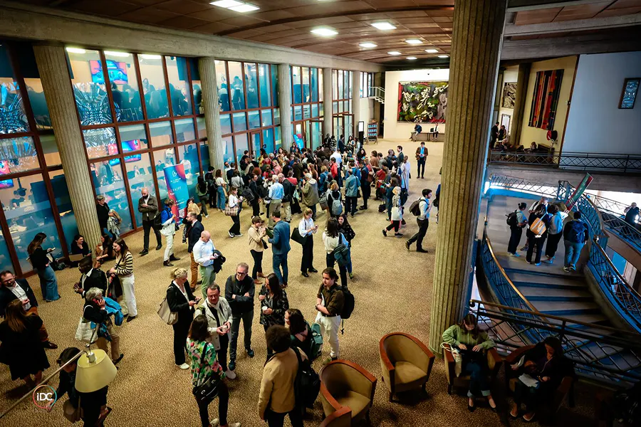 Attendees networking during the Sommet de la Mesure d'Impact in a large conference venue, showcasing smooth crowd flow, informal exchanges and a dynamic on-site attendee experience.