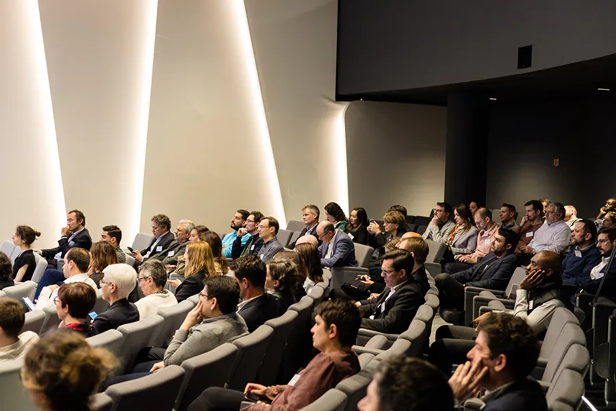 Attendees seated in a conference room listening to a session during the Digital Habitat hybrid event