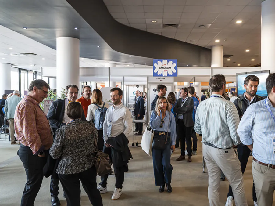 Attendees networking during a corporate event, exchanging and connecting in a professional environment with exhibitor booths and networking areas.