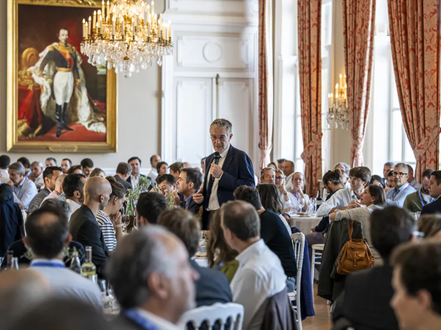 Attendees engaged in a conference session at a corporate event, with a speaker addressing the audience in a formal setting.
