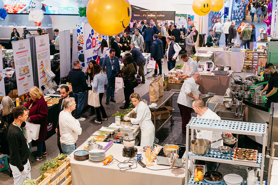 Attendees engage with exhibitor booths and watch live cooking demonstrations on the trade show floor. A high-energy example of on-site attendee experience at a large-scale B2B foodservice event, managed end-to-end with an all-in-one event management platform.