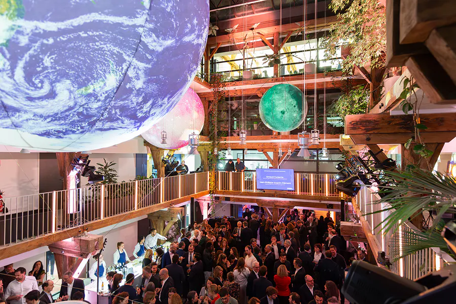 Vue en plongée de la salle lors de la cérémonie des Vœux 2026 de Grand Paris Aménagement, avec plusieurs centaines de participants réunis dans un espace végétalisé sur deux niveaux, agrémenté de sphères lumineuses suspendues. ©Gael_Kazaz