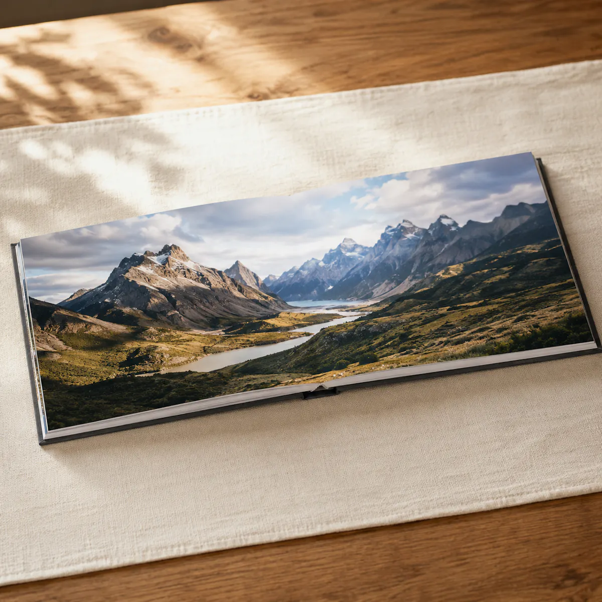 Fotolivro Premium aberto em spread panorâmico lay-flat, foto atravessando as duas páginas